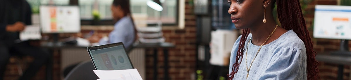 Isang babae ang nakaupo sa mesa sa opisina, nagre-review ng paperwork